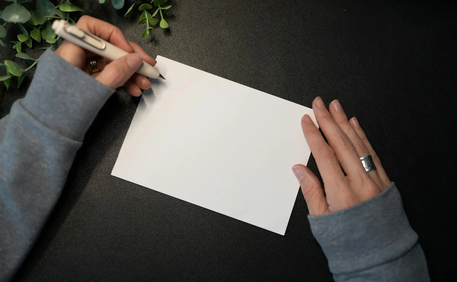 Zwei Hände mit Stift über einer leeren Karte, bereit für einen persönlichen Geburtstagsgruß