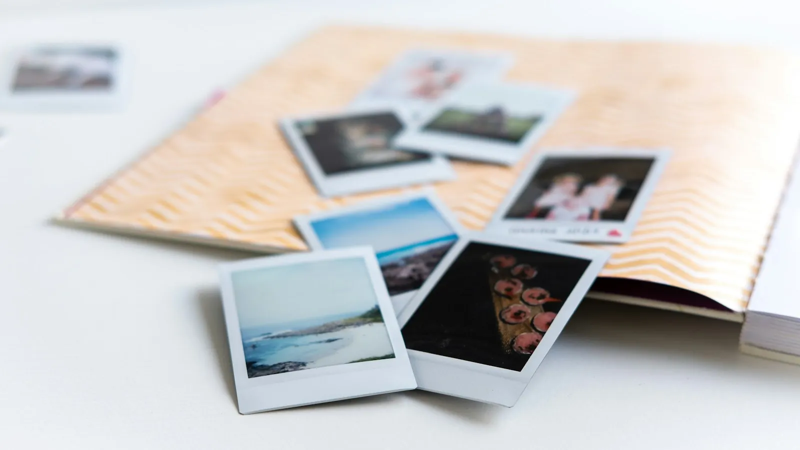 Polaroid-Fotos liegen auf einem aufgeschlagenen Erinnerungsalbum