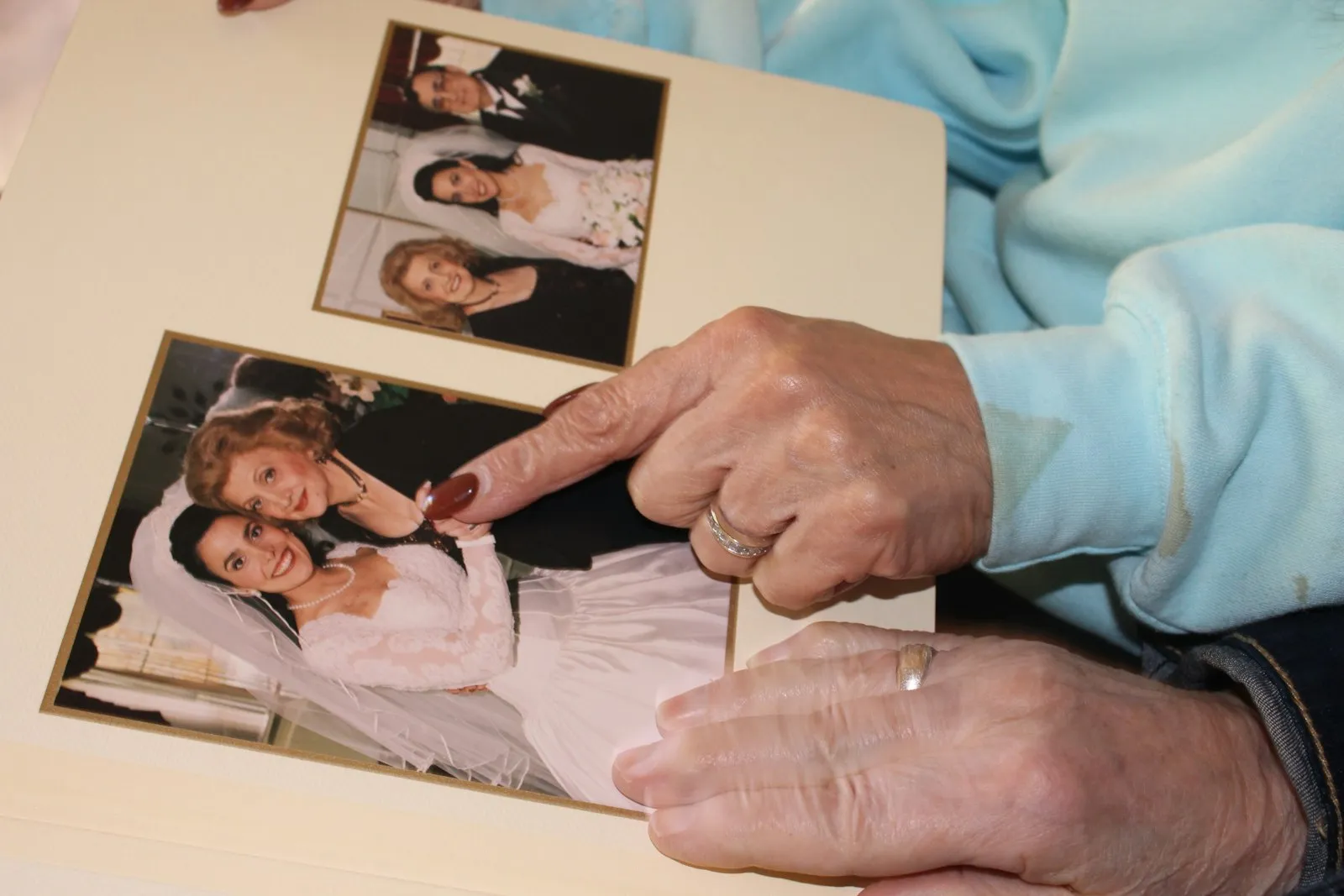Eine ältere Frau zeigt in einem Fotoalbum auf ein Familienfoto