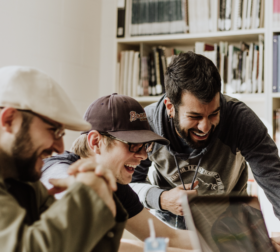 Group of people sitting around a laptop, smiling